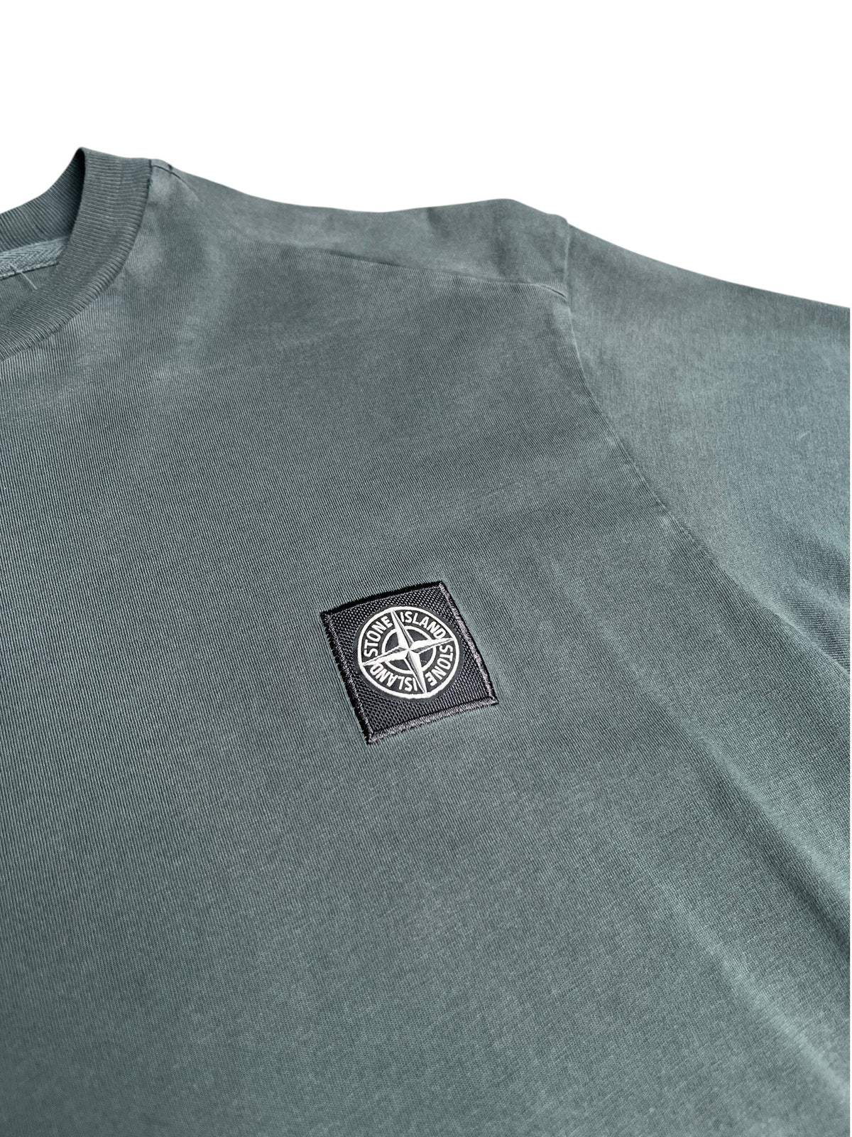 T-shirt vintage Stone Island vert délavé avec écusson logo brodé sur la poitrine, vendu par vinqo.store
