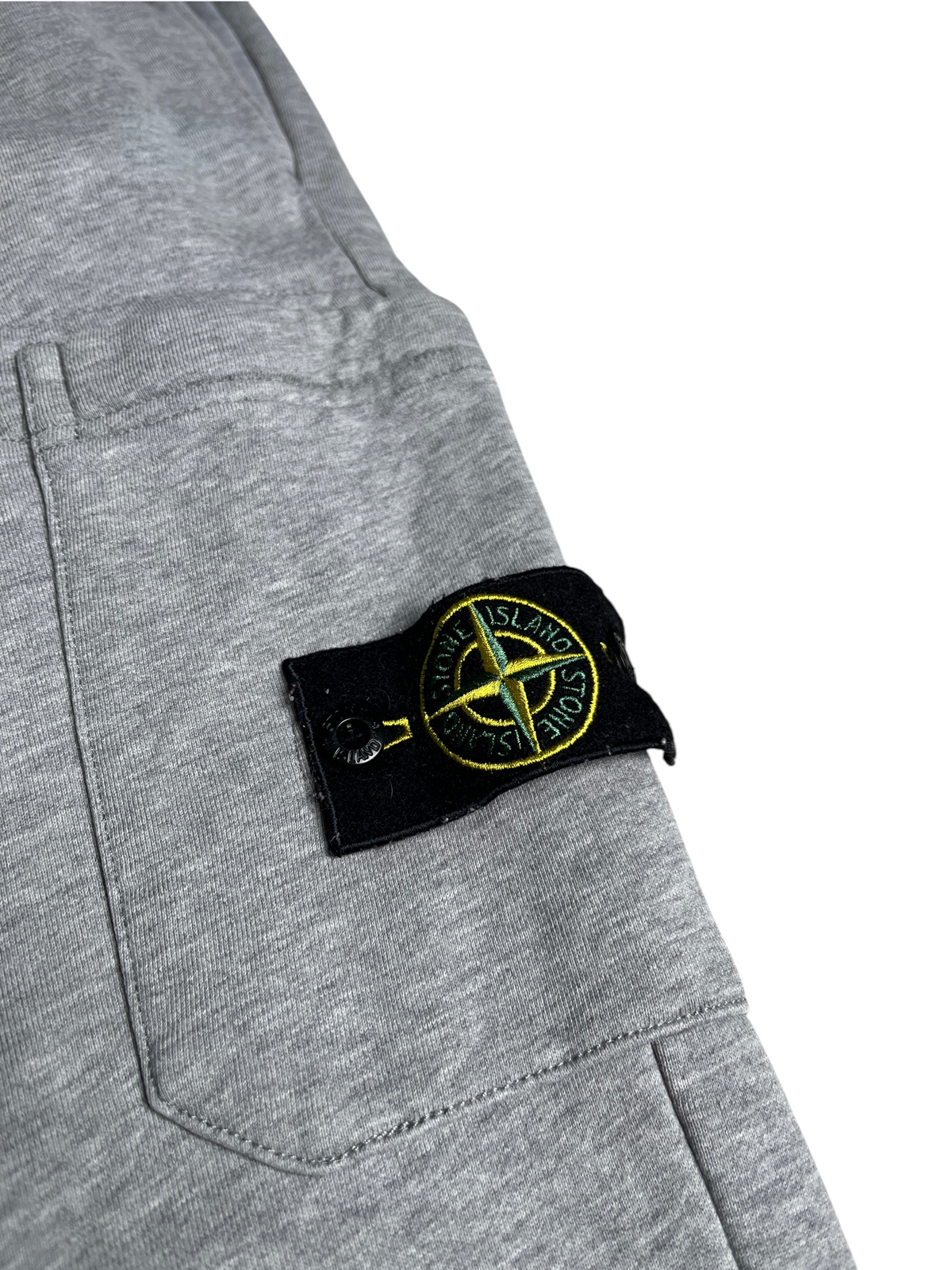 Pantalon de jogging gris vinqo.store avec écusson Stone Island emblématique sur la poche latérale