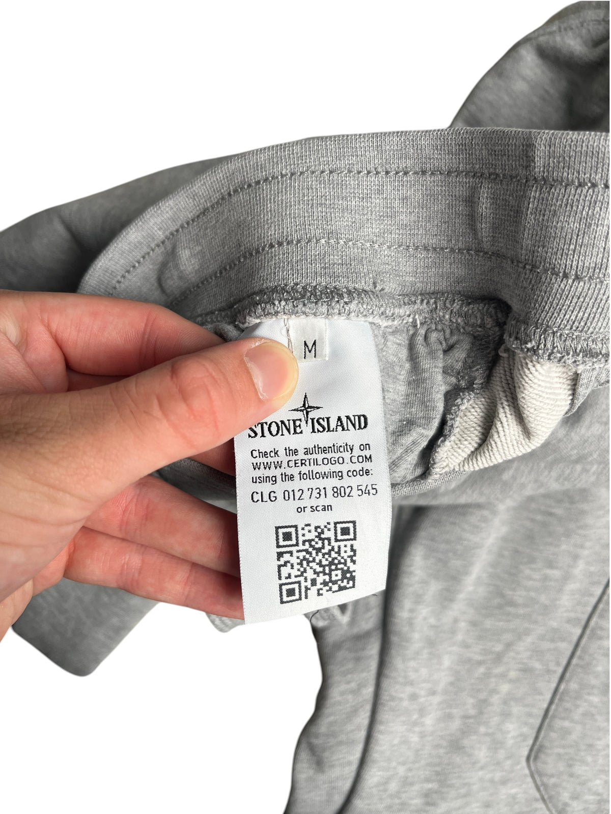 Etiquette d'authenticité intérieure d'un pantalon de jogging gris Stone Island taille M chez vinqo.store