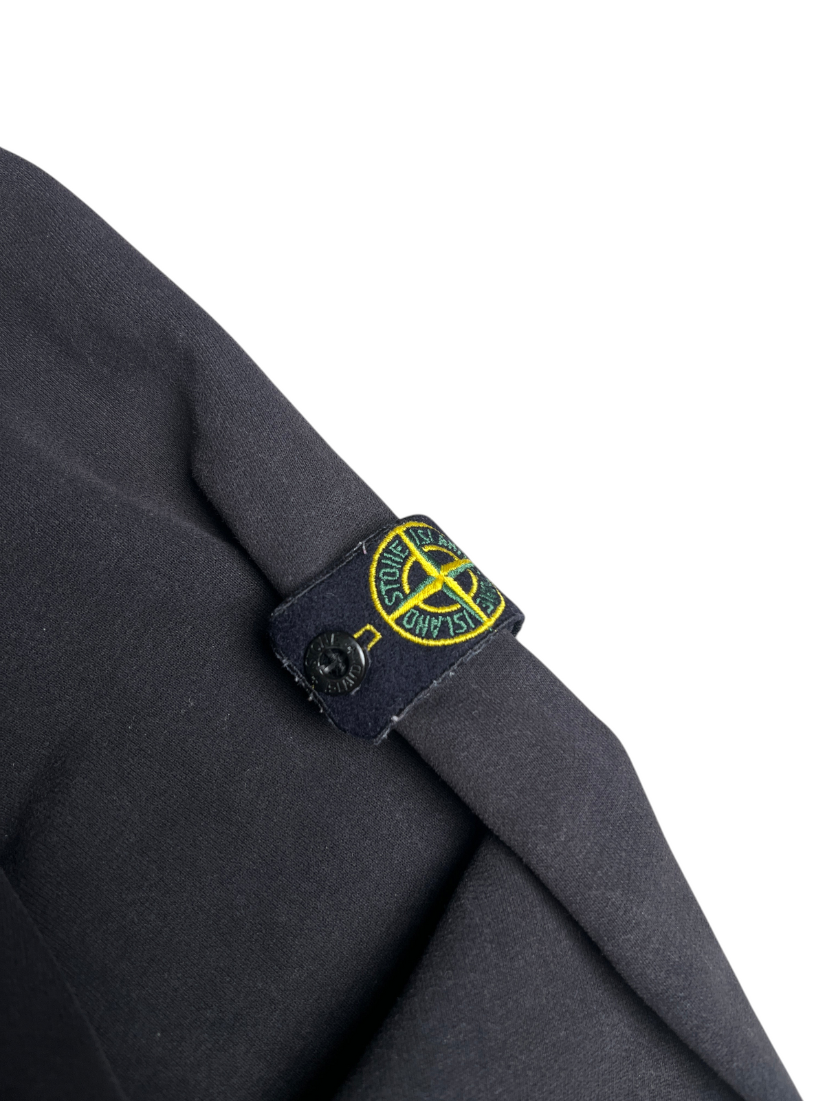 Gros plan sur le badge logo emblématique Stone Island sur la manche d'un sweat à capuche noir vinqo.store