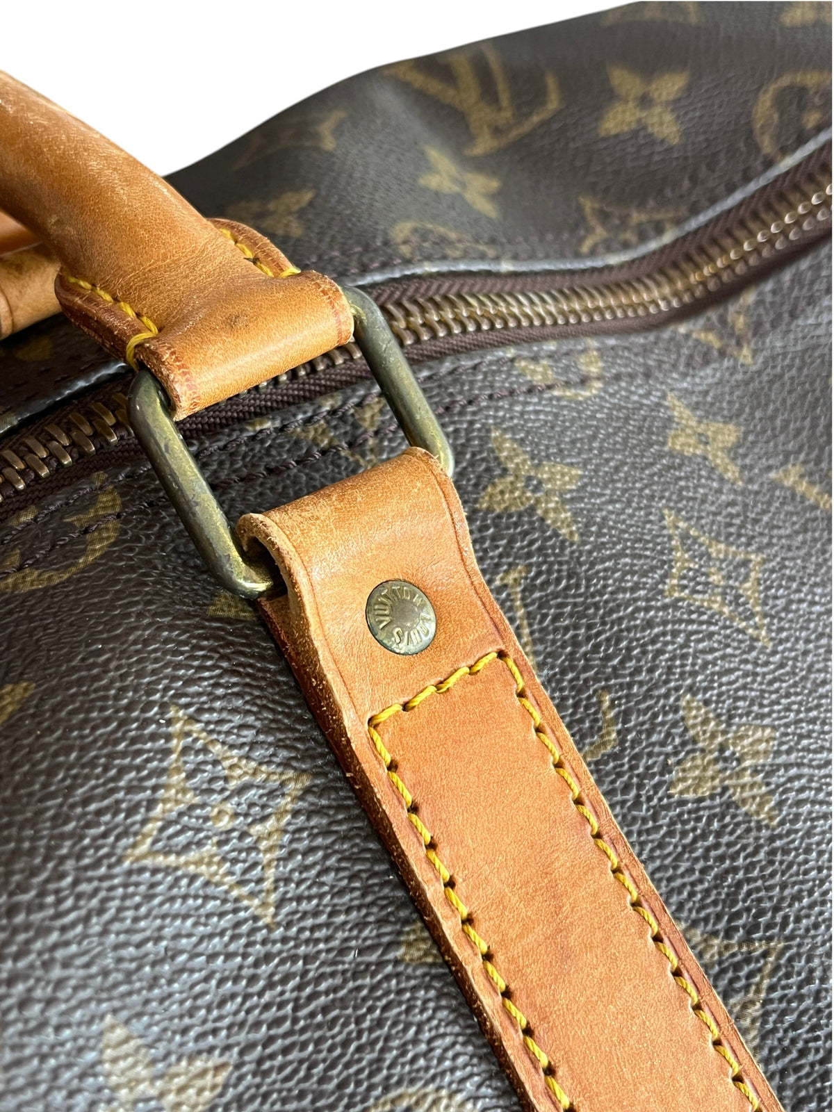 Détail du sac de voyage vinqo.store Louis Vuitton Keepall 55 en toile monogram marron avec finitions en cuir naturel