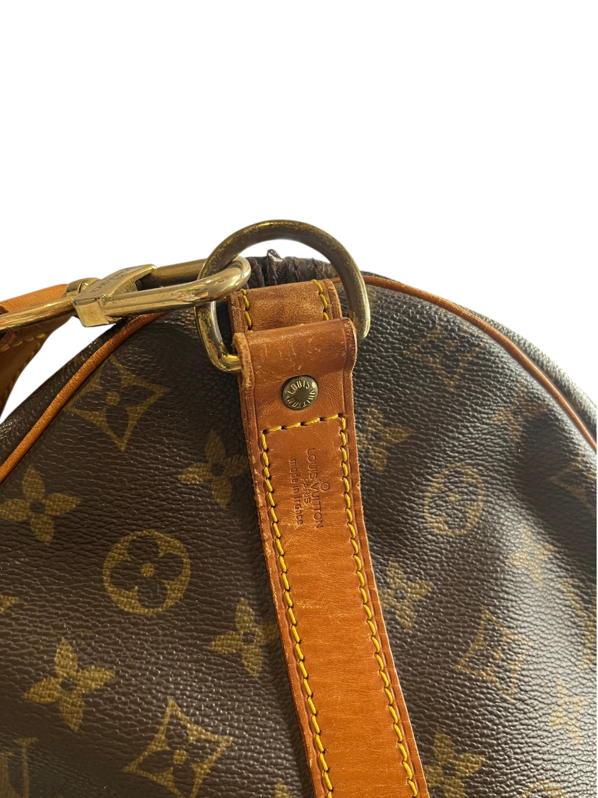 Détail de la bandoulière et de la boucle en laiton sur un sac de voyage Louis Vuitton Keepall 55 chez vinqo.store
