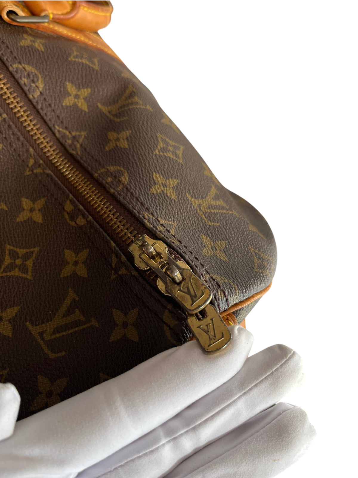 Détail de la fermeture éclair dorée sur un sac de voyage Louis Vuitton Keepall 55 en toile monogram vinqo.store