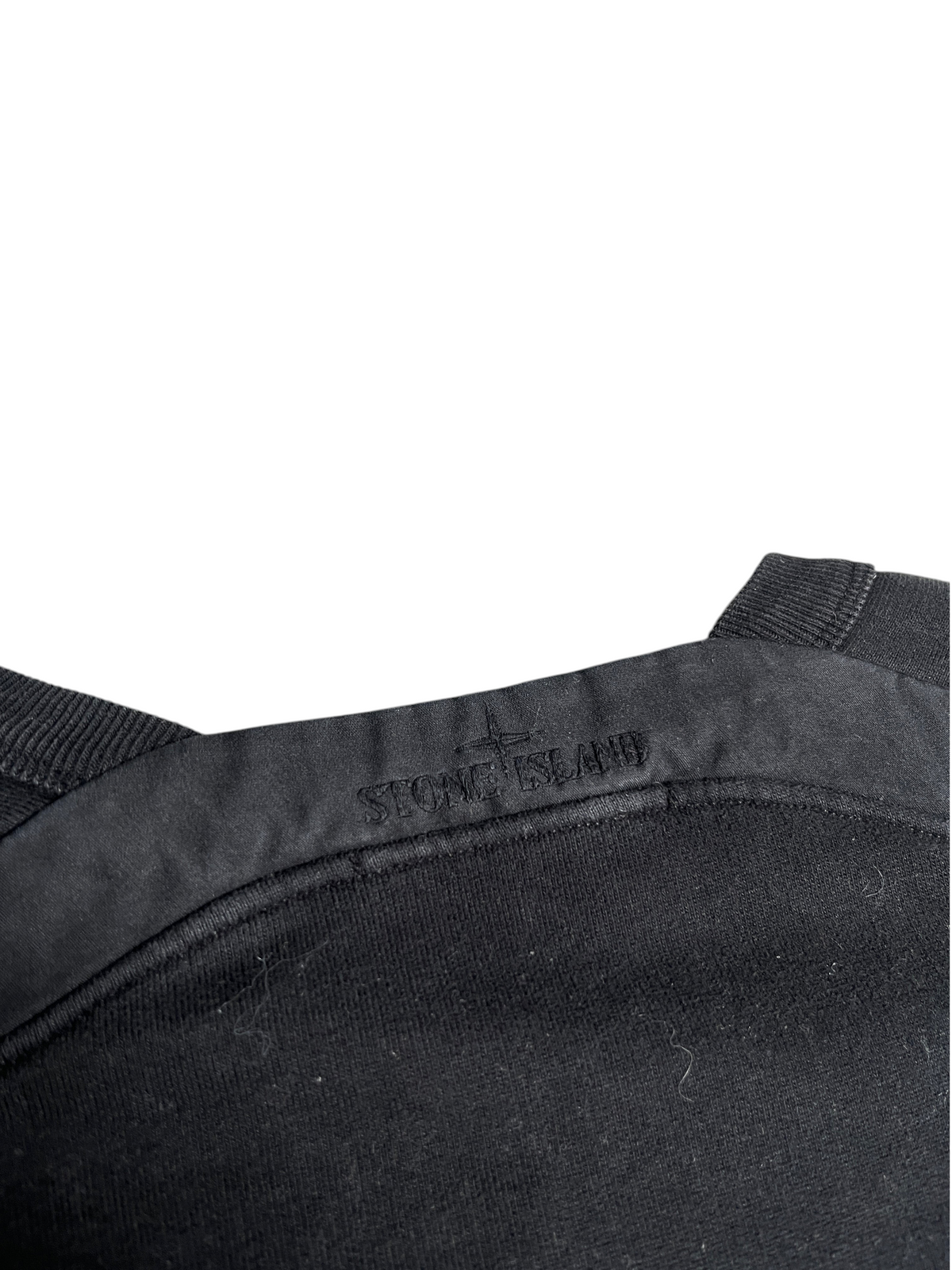 Détail du col d'un sweat-shirt noir Stone Island vintage avec logo brodé ton sur ton, proposé par vinqo.store