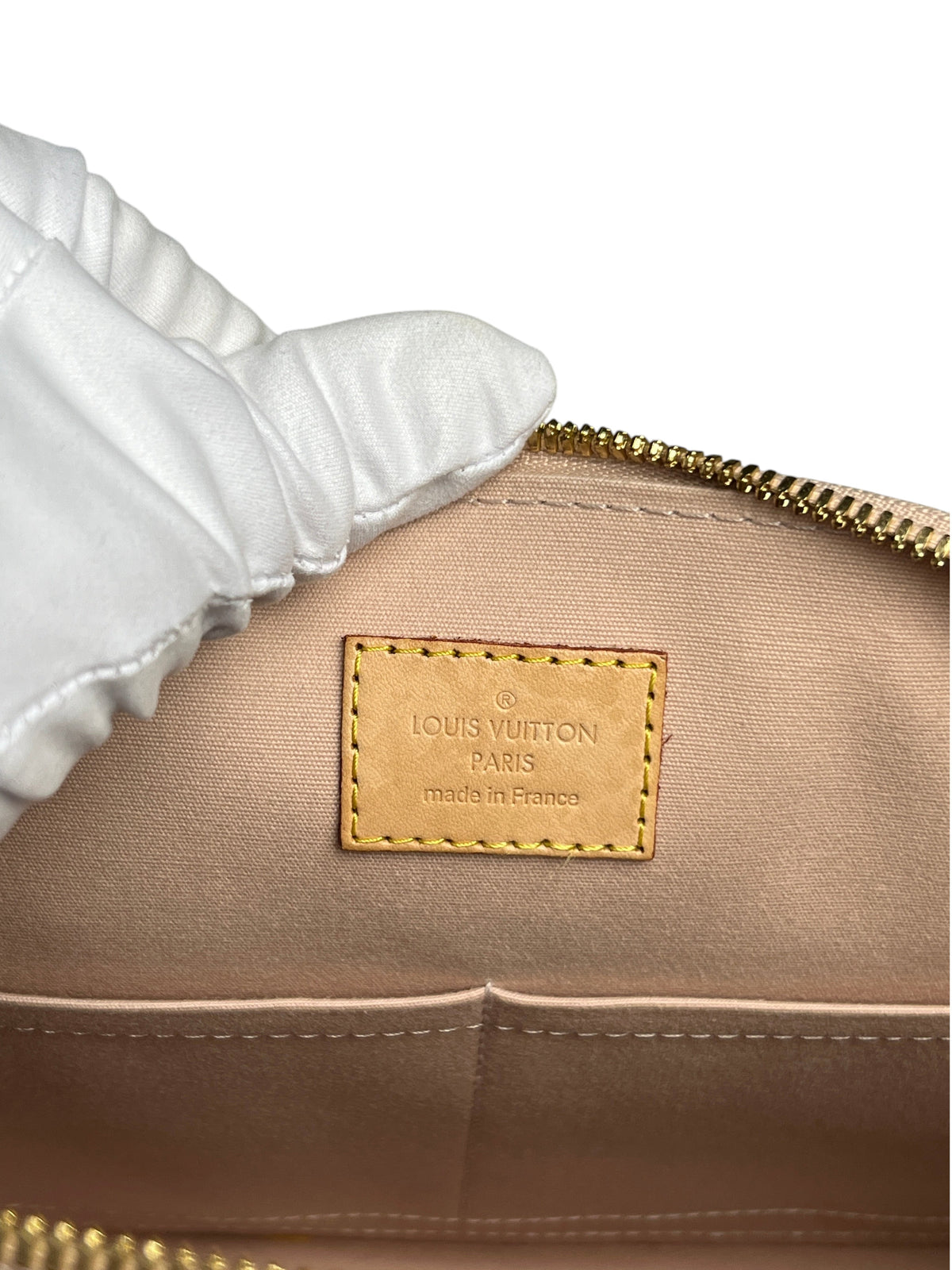 Etiquette intérieure en cuir beige avec logo Louis Vuitton embossé dans un sac Alma PM de vinqo.store