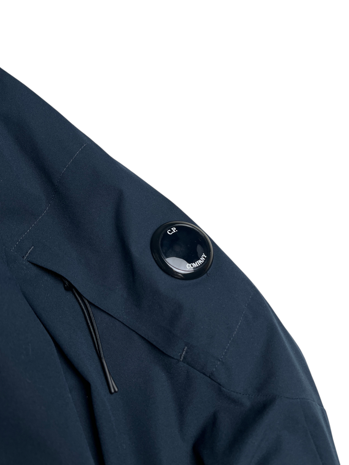 Détail de la manche d'une veste vinqo.store C.P. Company bleu marine avec la lentille iconique sur la poche