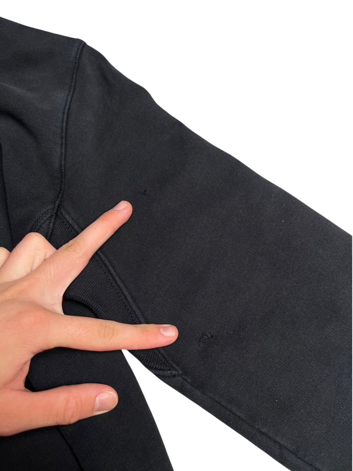 Manche de sweat à capuche noir Stone Island de vinqo.store montrant deux petits défauts sur le tissu