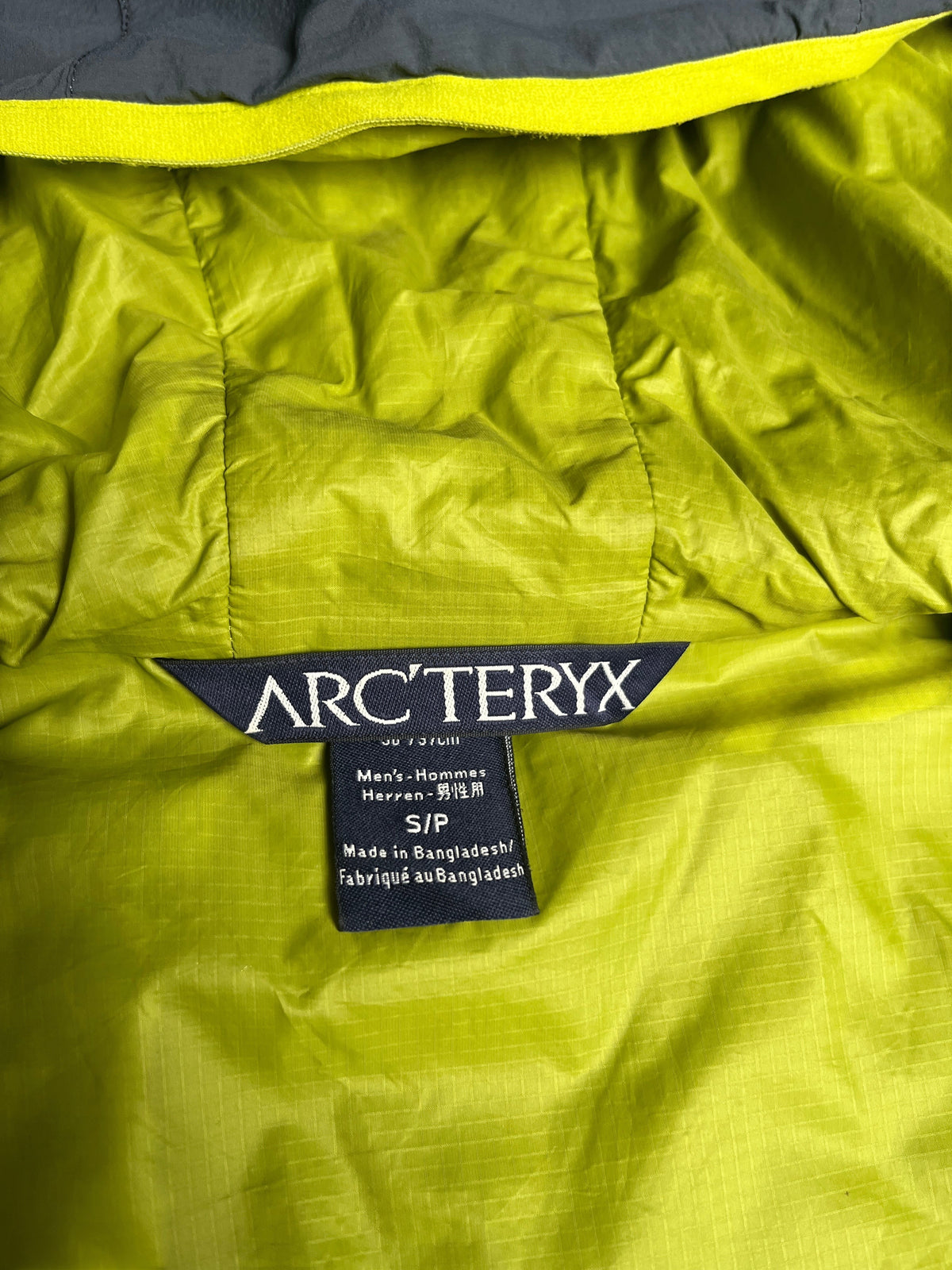Étiquette de col vinqo.store sur veste Arc'teryx Atom LT vert lime avec fermeture éclair jaune