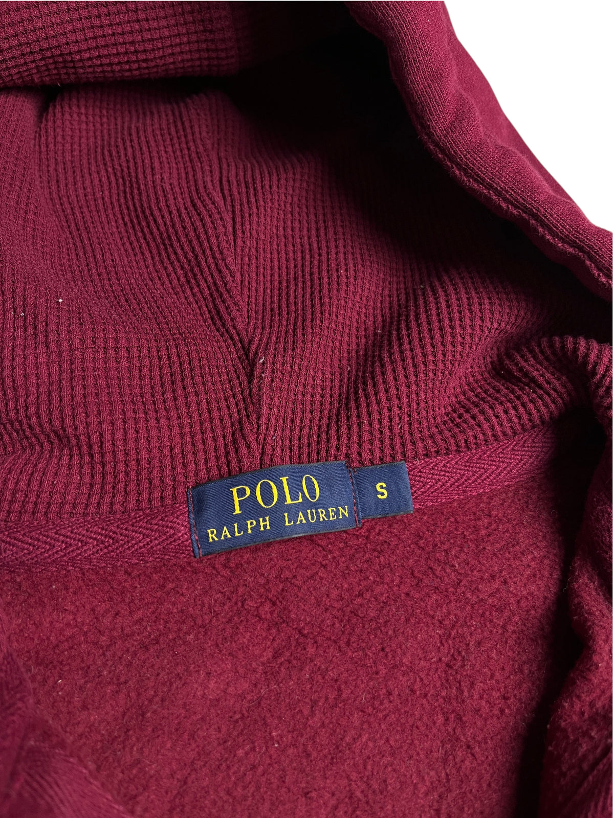 Gros plan sur l'étiquette Polo Ralph Lauren d'un sweat à capuche bordeaux en maille gaufrée de vinqo.store