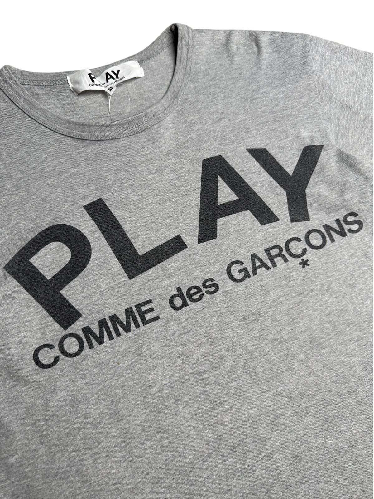 T-shirt gris chiné vinqo.store avec logo PLAY COMME des GARÇONS imprimé en noir sur la poitrine