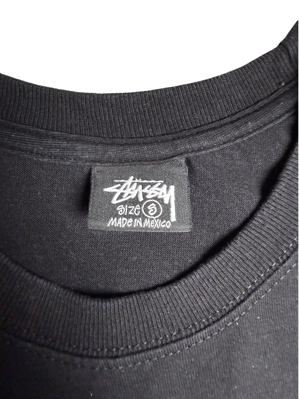 Étiquette de col noire d'un t-shirt Stussy taille S de la boutique vinqo.store avec logo et mention made in mexico